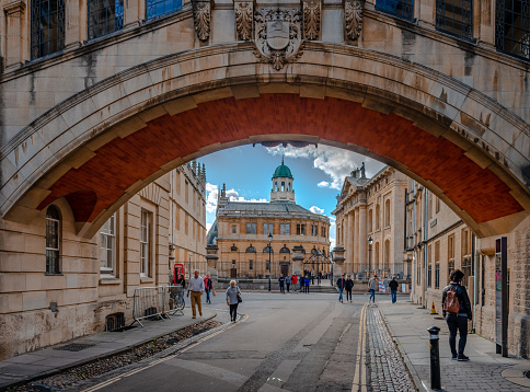 Oxford, UK - September 21 2018: The Bodleian library (on the left), the Sheldonian Theatre and the Clarendon Building (on the right) seen through the arch of the Hertford Bridge, aka Bridge of Sighs, that spans the New College Lane.