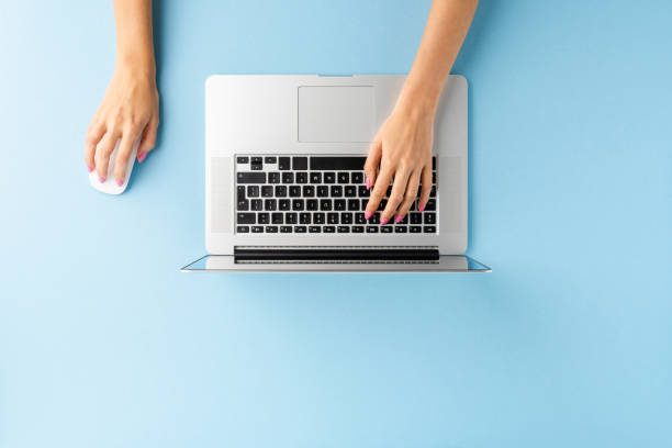 toma aérea de manos femeninas usando computadora portátil en computadora de escritorio de oficina azul. antecedentes empresariales. lay plano - computer human hand computer mouse internet fotografías e imágenes de stock