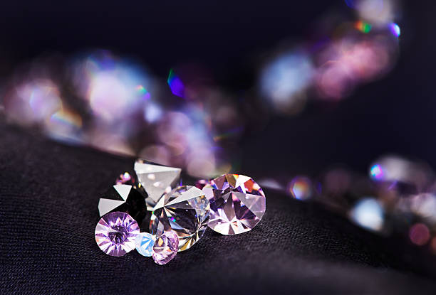 Diamond (small purple jewel) stones heap over black silk cloth stock photo