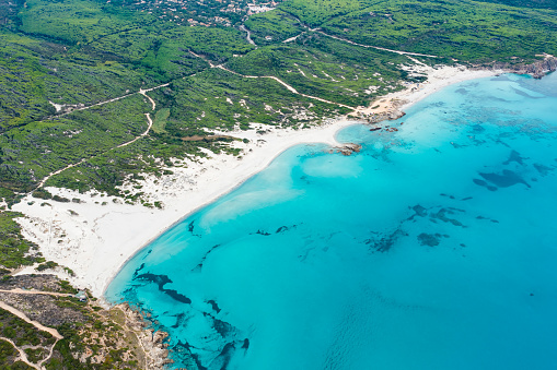 View from above, stunning aerial view of a white sand beach bathed by a turquoise water. Rena Majore, Sardinia, Italy.