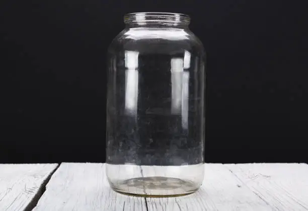 Photo of Empty glass jar on a black background.