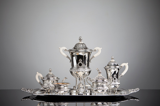 Horizontal high angle closeup photo of a collection of polished silverware on a linen cloth on a silver tray.