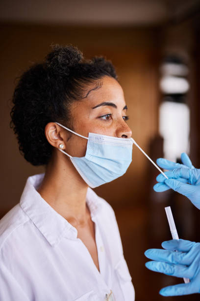 istock Woman in a mask having a nasal swab done by a frontline worker 1351428661