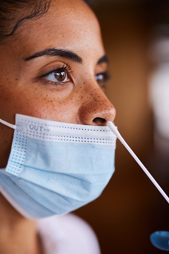 Close-up of a young woman wearing a protective face mask getting a nasal swab for a rapid coronavirus text at a medical clinic