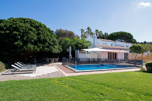 Exterior of luxury villa with garden and fenced swimming pool