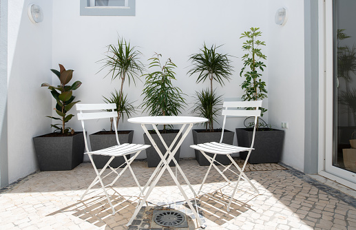 Internal patio courtyard with white metal table and chairs and planters