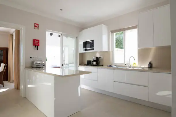 Brand new modern kitchen with white cabinets and beige stone counter top and ceramic tiled floor