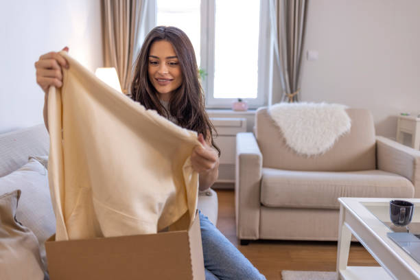istock Overjoyed woman seated on sofa hold on lap small cardboard box open parcel client feels satisfied bought goods in internet 1351432493