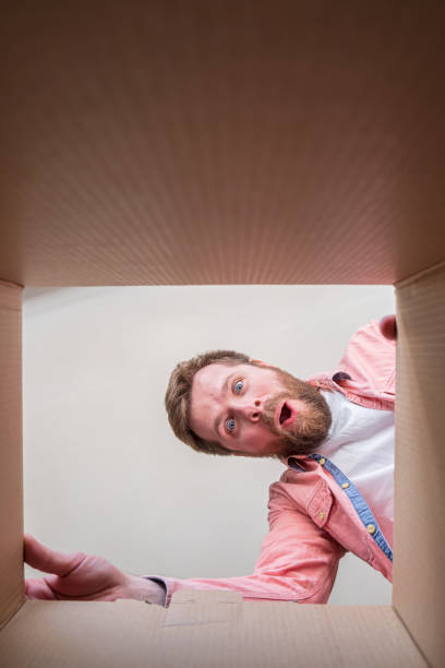 istock Contented, joyful bearded man unpacks a delivered box with a parcel or a gift. Unboxing inside view. Copy space. 1351434924