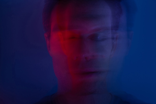 male portrait with close eyes in neon light, face closeup with blur