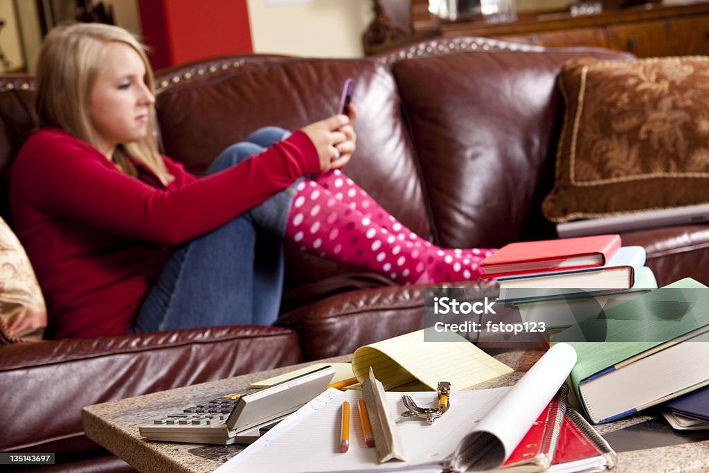 Adolescente indossando calze a pois sul divano SMS cellulare - Foto stock royalty-free di 16-17 anni