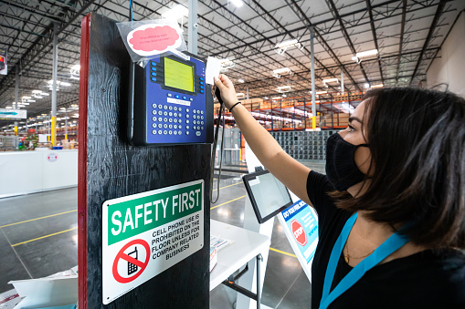 A young woman wearing a face mask clocks in at a fulfillment center.