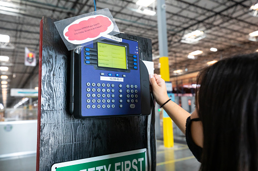 A young woman wearing a face mask clocks in at a fulfillment center.