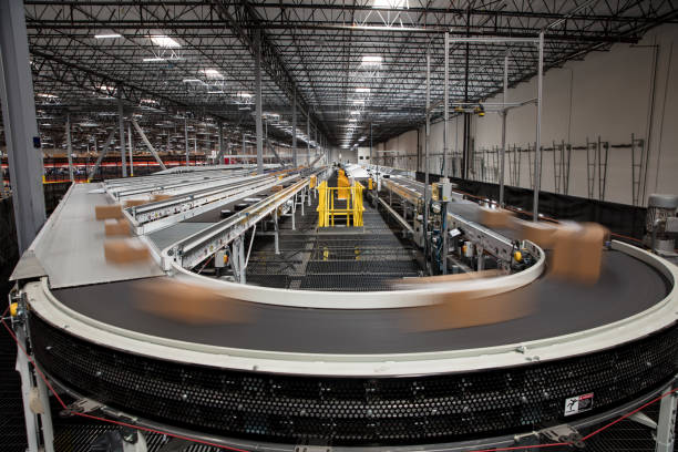 Long Exposure of Packages on Conveyor Belt Packages blur as they rush past on the complex conveyor belt system that sorts them for delivery at a large fulfillment center. production line stock pictures, royalty-free photos & images