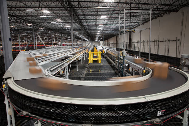 Long Exposure of Packages on Conveyor Belt Packages blur as they rush past on the complex conveyor belt system that sorts them for delivery at a large fulfillment center. automated stock pictures, royalty-free photos & images