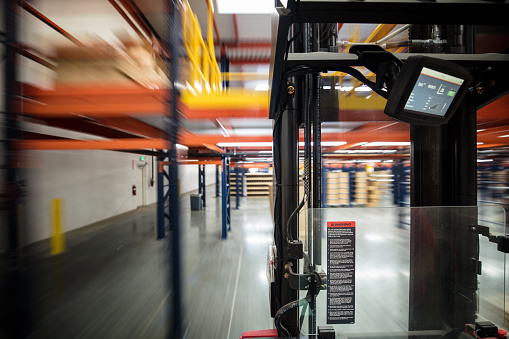 Long exposure shot taken from a camera mounted on a forklift moving around a massive fulfillment center.
