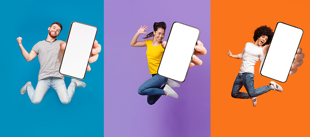Active happy emotional young diverse people hipsters jumping and showing device with blank screen, isolated on colorful background. Great offer, huge sale and mobile app, advise and website recommend