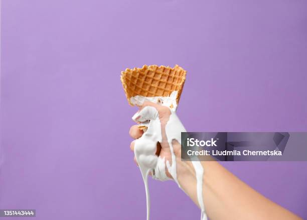 Woman Holding Crushed Wafer Cone With Molten Ice Cream On Violet Background Closeup Stock Photo - Download Image Now