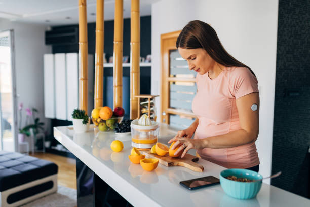 une belle jeune femme enceinte coupe des oranges et des citrons dans la cuisine pour faire du jus pressé - one person women human pregnancy beautiful photos et images de collection