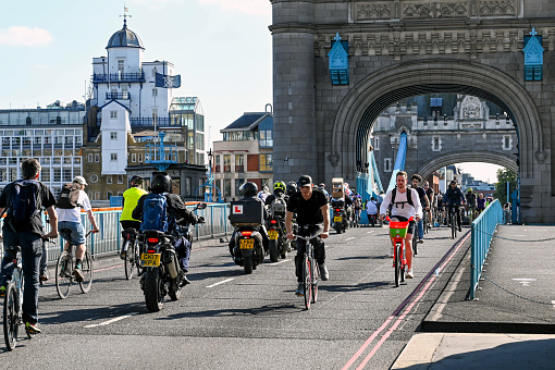 London, England - August 2021: People cycling and riding motorbikes across Tower Bridge