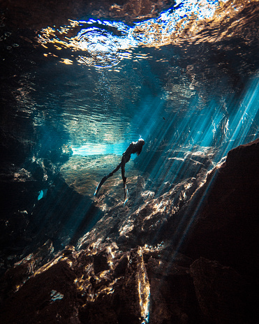 A Japanese Freediver swimming and enjoying the beauty of a Mexican Cenote