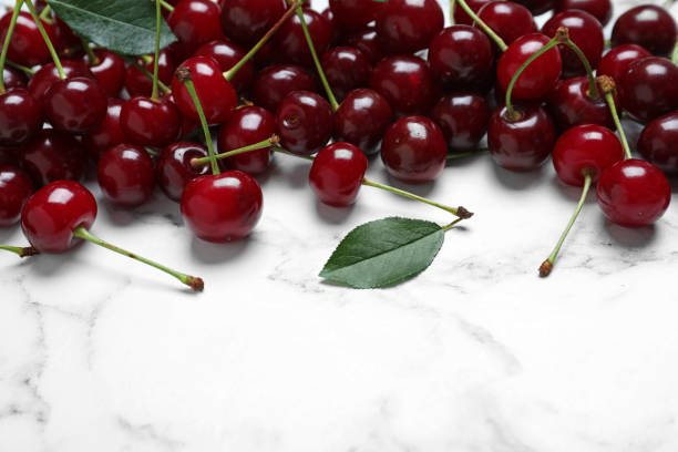 istock Sweet juicy cherries on white marble table, closeup 1351444154
