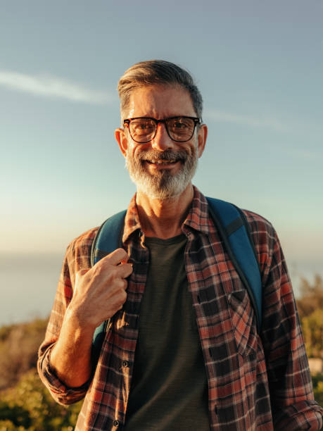 istock Cheerful mature hiker smiling at the camera while standing on a hilltop 1351445091