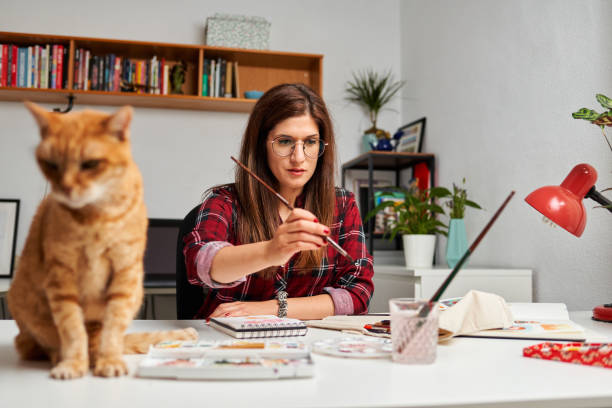 istock Illustrator painting in her studio with her cat on the desk 1351445220
