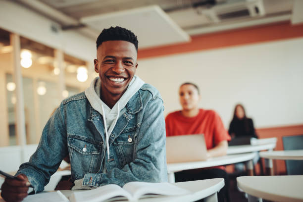 African student sitting in classroom African student sitting in classroom. Male student smiling during the lecture in high school classroom. education building photos stock pictures, royalty-free photos & images
