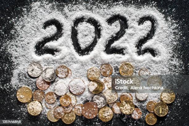 Hand Written Year 2022 And Various Coins Covered With White Sea Salt Such As Snow On Black Background Stock Photo - Download Image Now