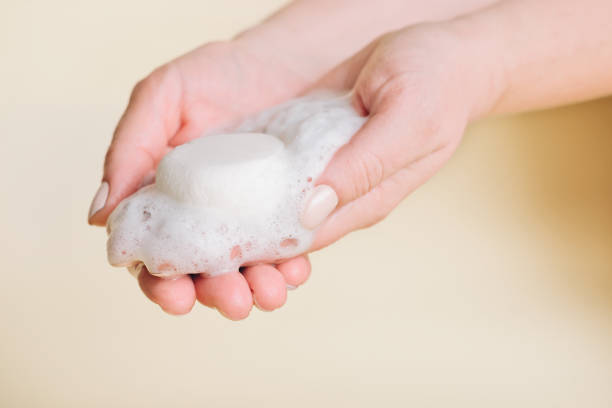 fester riegel shampoo in frauenhänden mit schaum. alternative art von shampoo. umweltfreundliches selbstpflegeprodukt. kosmetik ohne kunststoffverpackung, umweltfreundlich, zero waste - shampoo stock-fotos und bilder