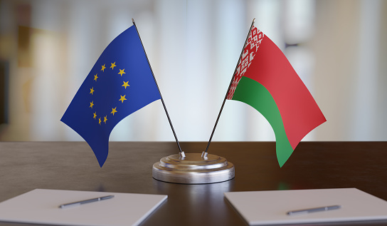 Belarussian and EU flags on table. Negotiation between European Union and Belarus. 3D rendered illustration.