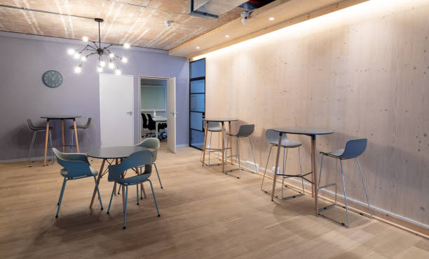 istock Empty chairs arranged around tables on hardwood floor in illuminated office 1351449919