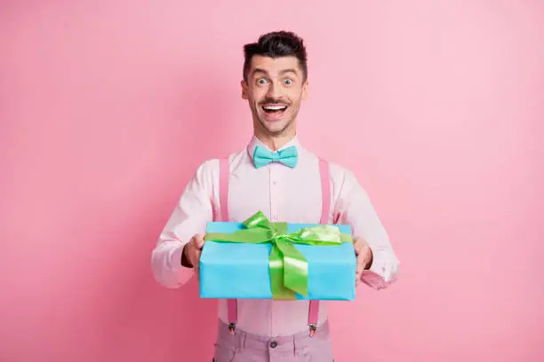 Photo of Photo portrait of cheerful guy receiving present isolated on pastel pink colored background