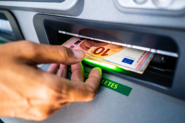 Close-up of the hand of a person withdrawing euro cash from an ATM machine stock photo