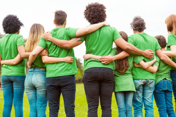 volontari maschi e femmine insieme al parco - green t shirt foto e immagini stock