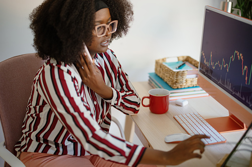 Woman entrepreneur analysing a cryptocurrency market graph at home office