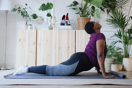 Young woman doing yoga asanas sun salutation in the morning at home