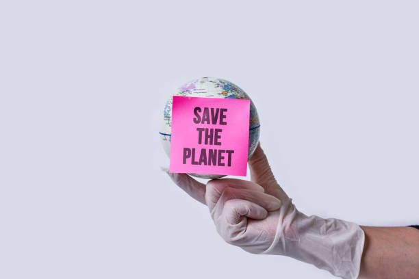 Hand in medical gloves holds a globe with note - save the planet stock photo