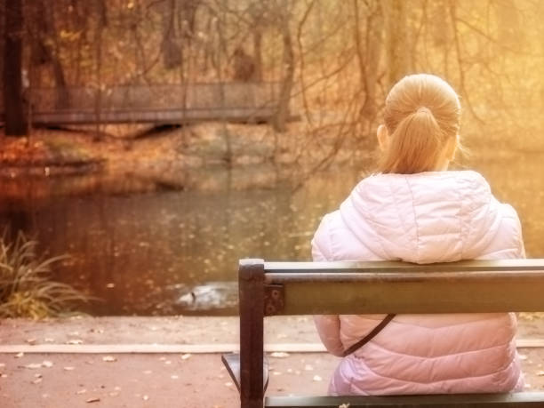 istock A girl sits on a park bench with her back to the camera. 1351455362