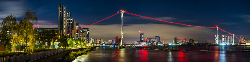 The towering pylons of the Emirates Air Line cable car over the River Thames illuminated at night in the heart of London, UK.