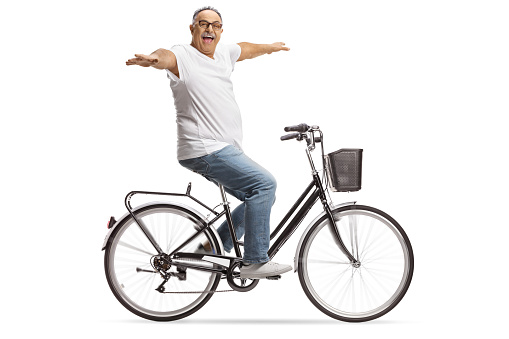 Happy mature man riding bicycle with arms wide open isolated on white background