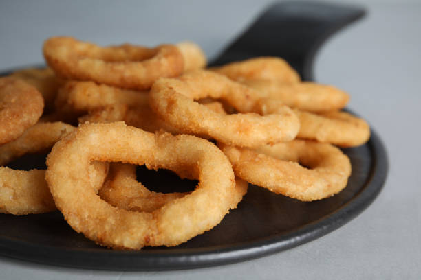 istock Slate plate with fried onion rings on grey table, closeup 1351459879