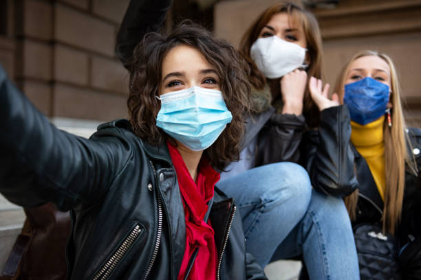 istock Female friends with face protective mask having fun taking a selfie 1351460871