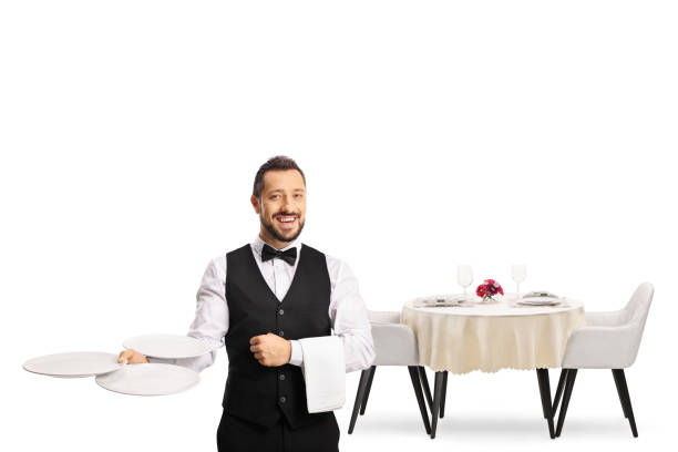 istock Server with a bow tie holding empty plates in front of a restaurant table 1351460955