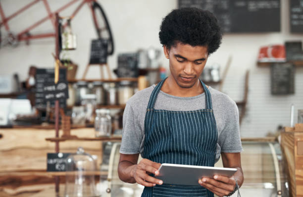 istock Shot of a young male waiter using a digital tablet at a cafe 1351461029