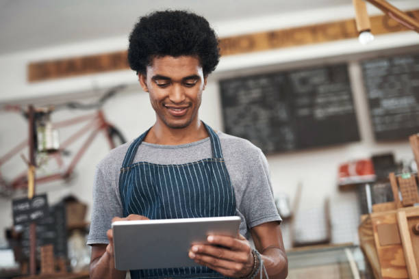 istock Shot of a young male waiter using a digital tablet at a cafe 1351461036