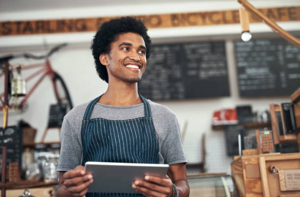 istock Shot of a young male waiter using a digital tablet at a cafe 1351461072