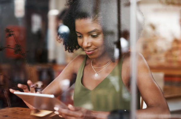 istock Shot of a young woman using a digital tablet at a cafe 1351461101