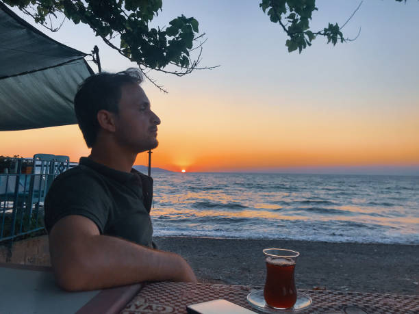 istock attractive man sitting looks at seascape during sunset 1351461323